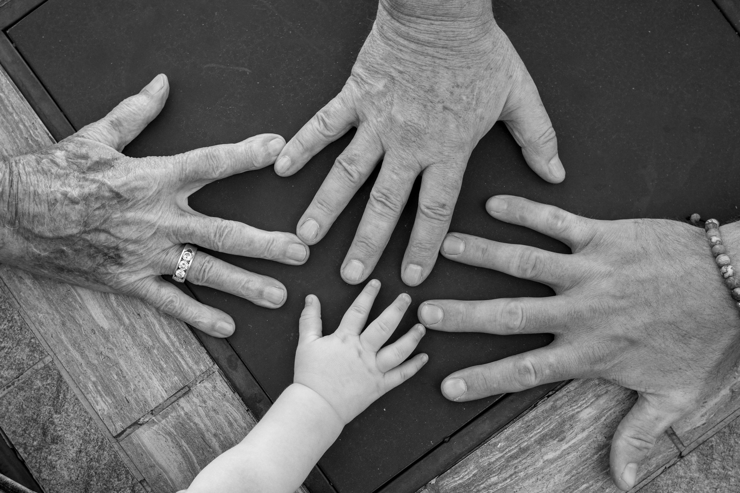 Hands from several generations gathered around a table